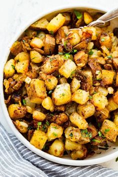 a white bowl filled with cooked potatoes on top of a blue and white towel