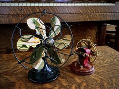 an old fashioned fan sitting on top of a table next to a small figurine