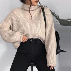 a woman in black jeans and a white turtle neck sweater is posing for the camera