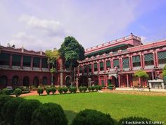 the building has many windows and balconies on each floor, along with lots of greenery