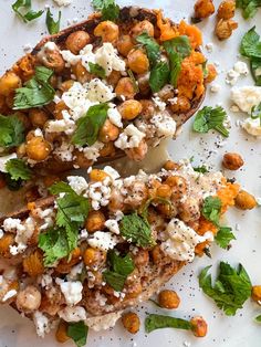 two pieces of bread topped with chickpeas, cheese and cilantro leaves