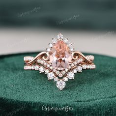 an engagement ring with a pink morganite surrounded by white diamonds on a green velvet box