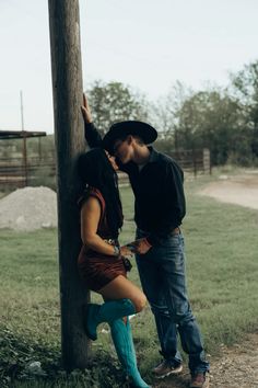 a man and woman leaning against a pole