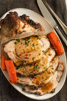 a white plate topped with meat and carrots next to a silver fork on top of a table