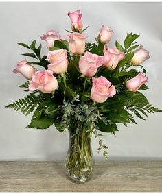 a vase filled with pink roses on top of a wooden table