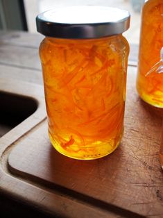 two jars filled with orange liquid sitting on top of a wooden table