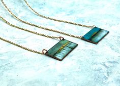 "Landscape inspired enamel rectangle necklace on a 18\" delicate gold plated chain. The pendant measures approximately 30mm x 15mm . Layers of vitreous enamel were used to build up the depth and variation in colour over a number of firings, 24ct gold foil added at the final stage to produce a 'watercolour' effect landscape. Each piece is unique and variations are dependent on firing times and interactions between the properties of different enamels. The back of the pendant has been enamelled for Handmade Rectangular Brass Necklace, Blue Patina Necklace Perfect For Gifts, Gift Blue Patina Necklace, Gold Enamel Jewelry With Soldered Details, Rectangular Patina Jewelry As Gift, Gold Pendant Necklace With Patina, Unique Green Necklace With Rectangular Pendant, Handmade Artistic Necklace With Rectangular Shape, Artistic Gold Hand Painted Necklace