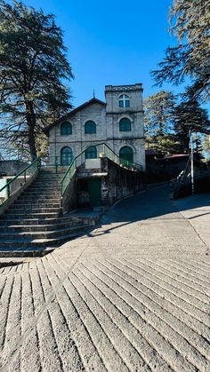 an old building with steps leading up to it and trees on the other side in front