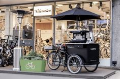 there is a bike that is parked in front of the store with an umbrella over it