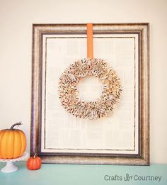 a frame with a wreath on it next to a small pumpkin