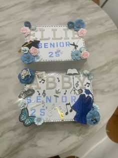 two decorated letters sitting on top of a white table next to a blue and pink flower