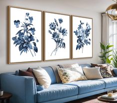 three blue flowers are hanging on the wall above a couch in a living room with a large window