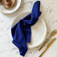 a white plate topped with a blue napkin next to a fork and knife on top of a table