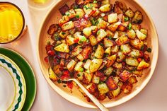 a plate full of potatoes next to some drinks and plates with utensils on them