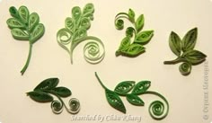 green paper quilling leaves and swirls on a white surface