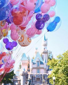 many balloons are floating in the air near a castle at disney world's magic kingdom