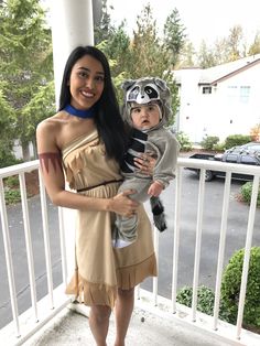 a woman is holding a baby dressed as a racoon and wearing a costume