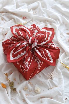 a red wrapped gift box sitting on top of a white sheet