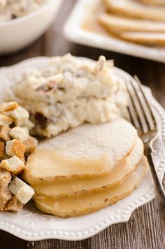 a close up of a plate of food with potatoes and meat on it, next to a fork