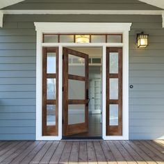 the front door of a house with wood flooring and two lights on each side