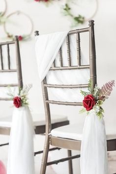 two chairs decorated with red roses and greenery for a wedding or special event,