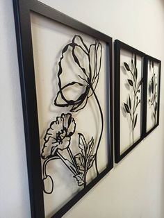 three black and white flowers are hanging on the wall next to each other in this room