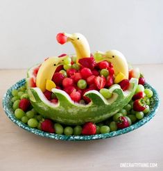 a watermelon fruit bowl with bananas, grapes and strawberries in the shape of dolphins