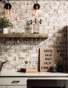 a brick wall in a kitchen with wine glasses on the shelf