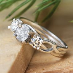 two wedding rings on top of each other with a flower in the middle and a diamond center