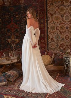 a woman in a white wedding dress standing on a rug with her back to the camera