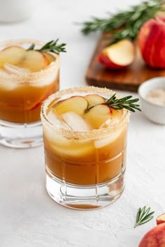 two glasses filled with apple cider on top of a table