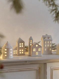 small white houses are lit up on the mantle