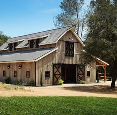 an old barn with a metal roof and two story windows on the side of it