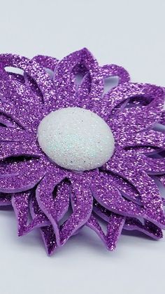 a purple and white flower brooch sitting on top of a table