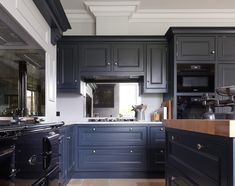 a kitchen with dark blue cabinets and wooden counter tops is pictured in this image from the front view