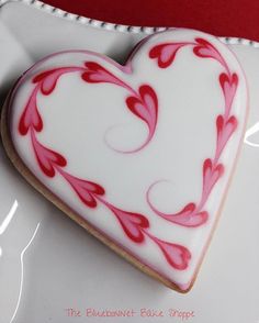 a decorated heart shaped cookie sitting on top of a white plate