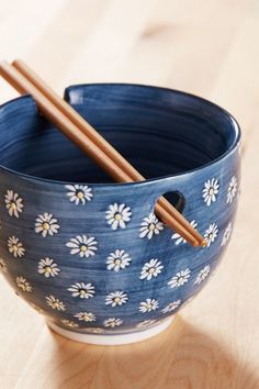 two chopsticks are sticking out of a blue bowl with daisies on it