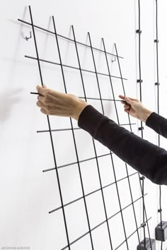 a woman is pointing at the wall with many wires attached to it