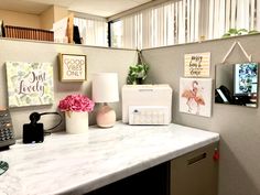 an office desk with flowers, phone and pictures on the wall