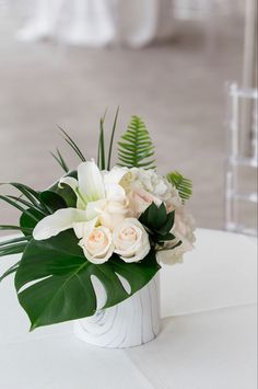 white flowers and greenery in a vase on a table