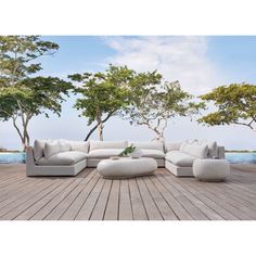 a large white couch sitting on top of a wooden floor next to trees and water