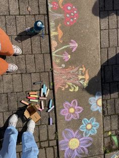 someone is standing on the sidewalk with chalk crayons