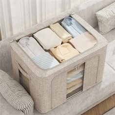 an open suitcase sitting on top of a couch next to pillows and pillow cases with folded clothes in it