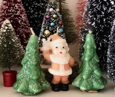 there is a small figurine in front of some christmas trees