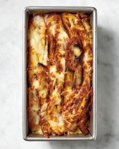 a casserole dish with cheese and meat in it on a marble countertop