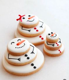 three decorated cookies with frosting on them sitting next to each other in the shape of snowmen