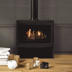 a fire place sitting on top of a wooden floor next to stacks of books and candles