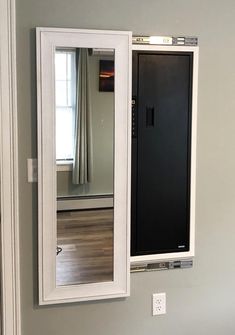 a bathroom mirror sitting on top of a wooden floor next to a wall mounted cabinet