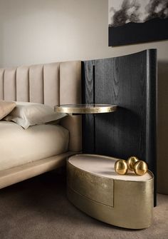 a bed sitting next to a table with two gold balls on it