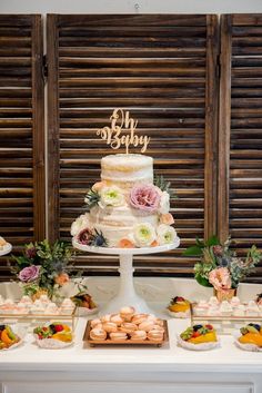 a table topped with a cake and lots of pastries next to wooden shutters